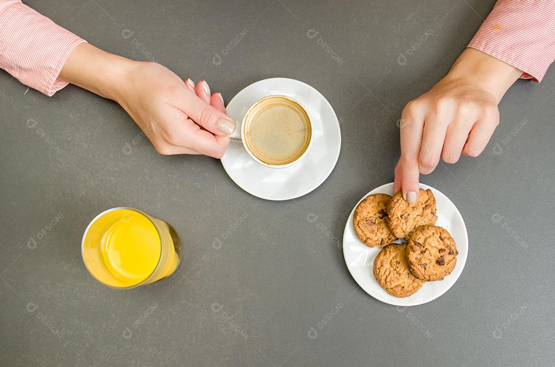 Mesa posta, café , biscoitos e suco com fundo escuro mulher segurando xicara