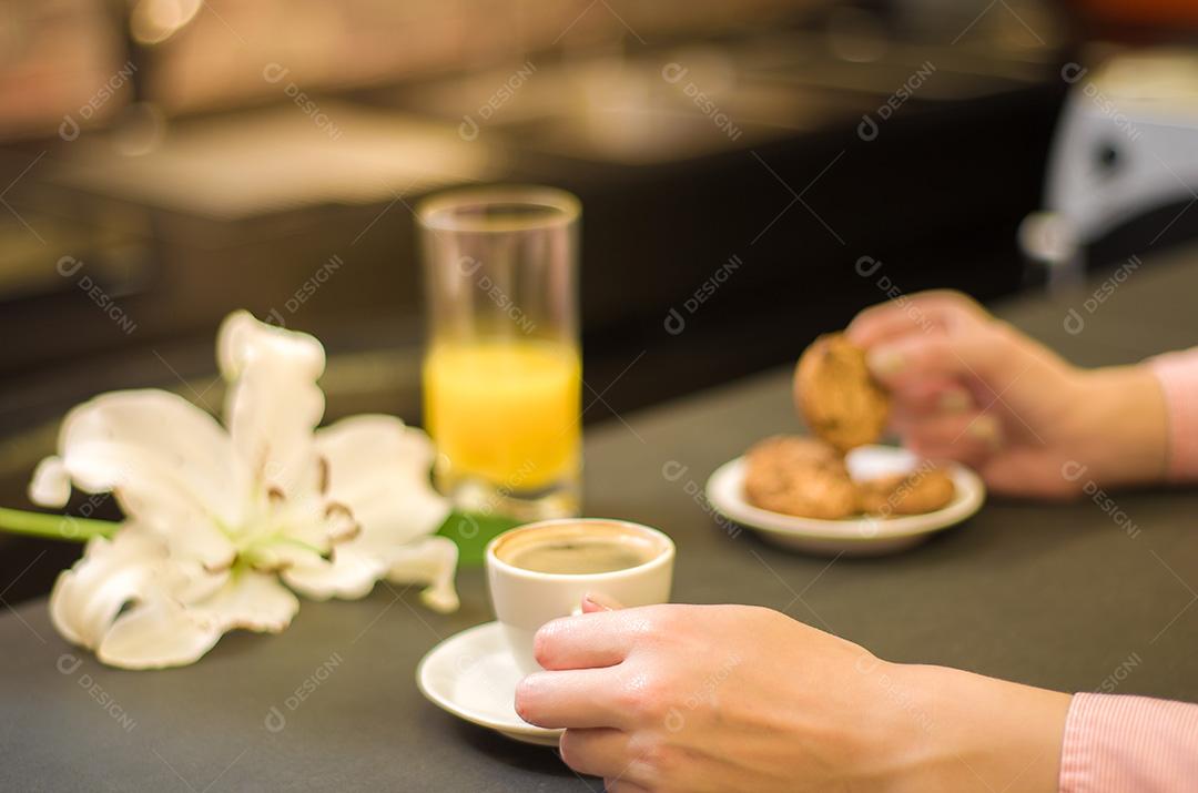 Mesa posta, café , biscoitos e suco com fundo escuro mulher segurando xicara