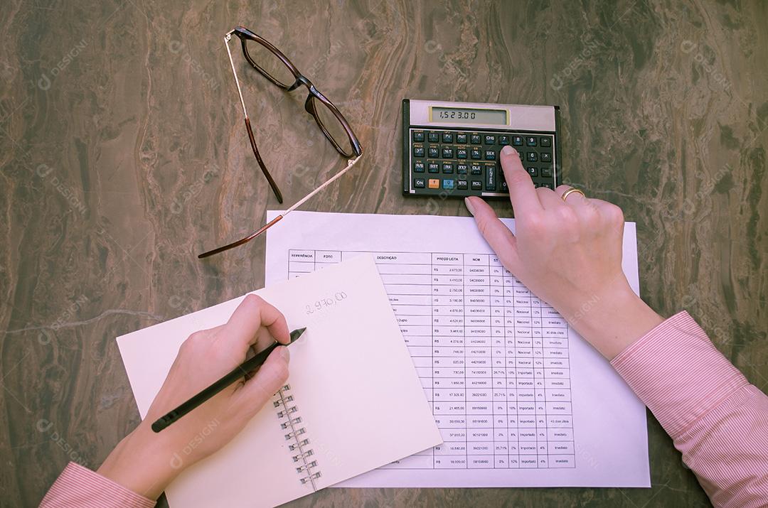 Contabilista feminina trabalhando em contas em análise de negócios com calculadora e planilhas