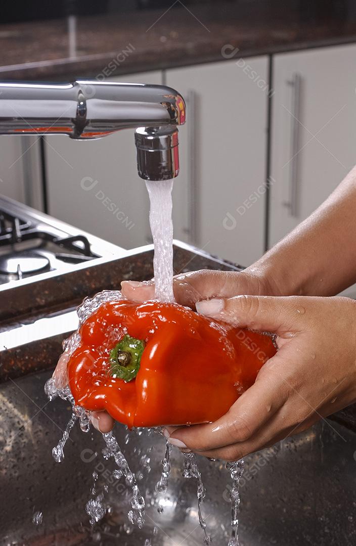 Pimenta vermelha sendo lavada na pia da cozinha.
