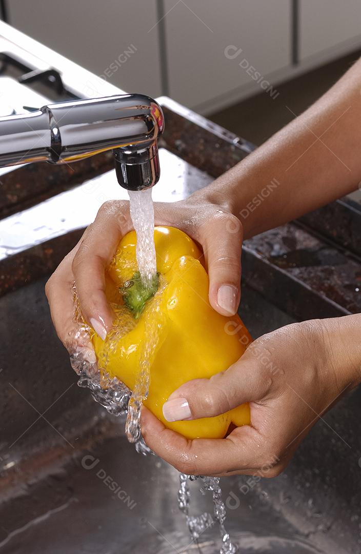 Pimenta amarela sendo lavada na pia da cozinha