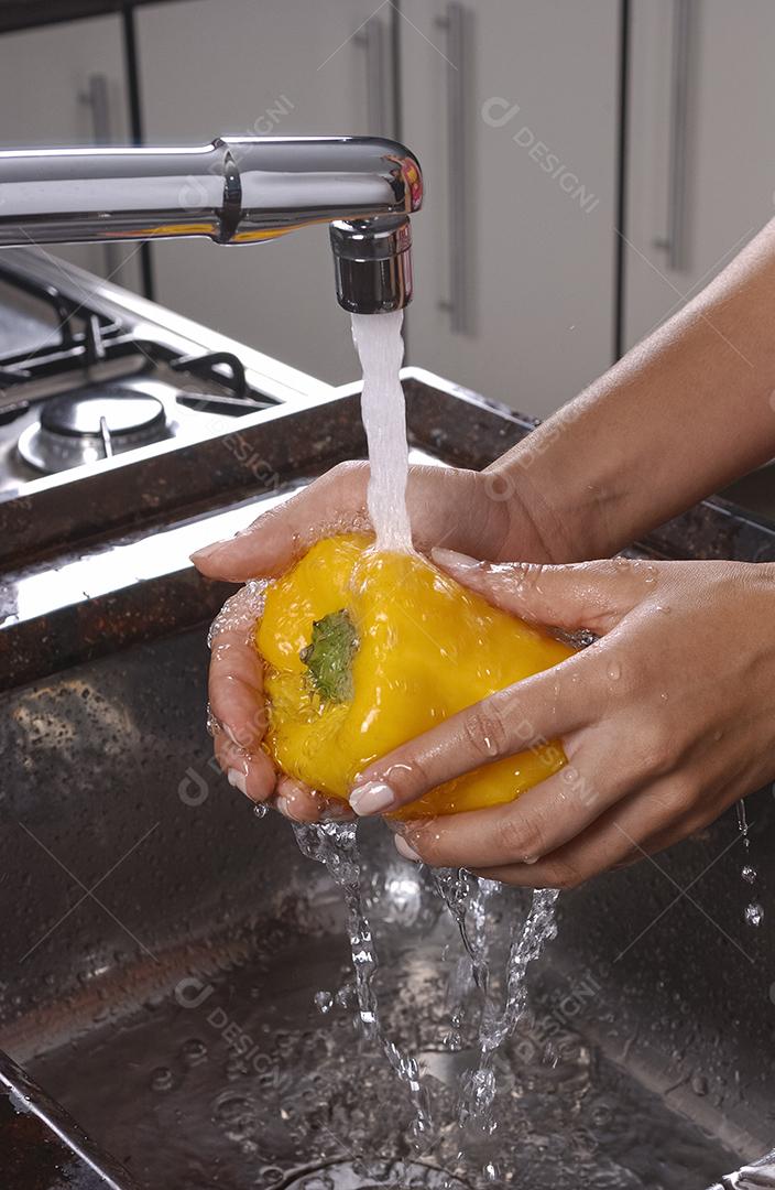 Pimenta amarela sendo lavada na pia da cozinha
