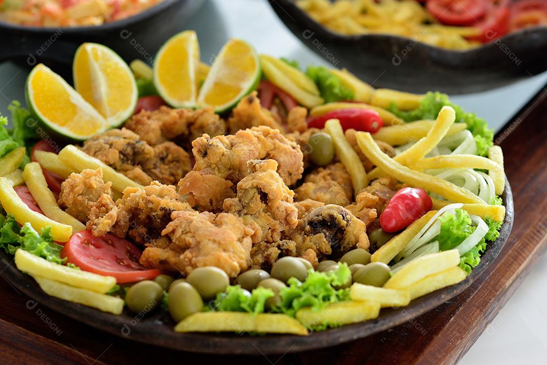 cozinha brasileira. Frango crocante servido com batatas fritas, salada e azeitonas. Esta iguaria é muito apreciada na região nordeste do Brasil