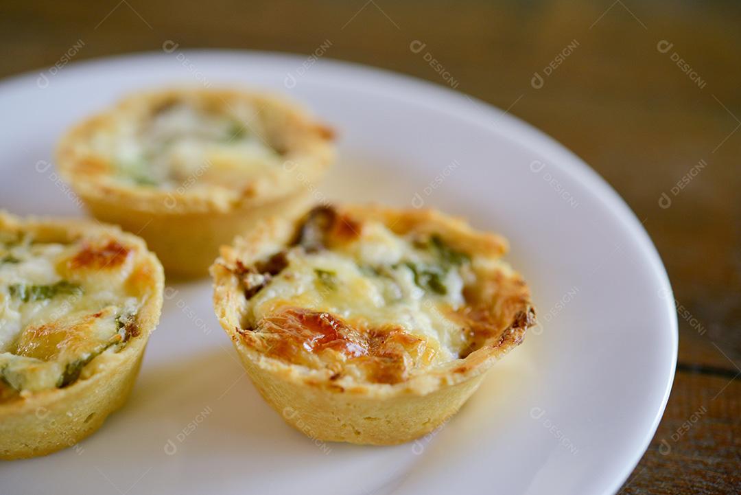 gastronomia brasileira. Tortas de queijo e carne seca com rúcula em prato artesanal na mesa de madeira.
