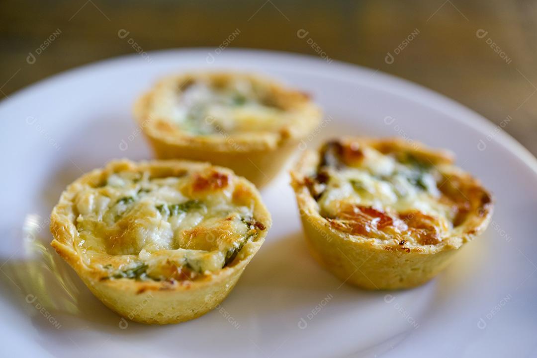 gastronomia brasileira. Tortas de queijo e carne seca com rúcula em prato artesanal na mesa de madeira.