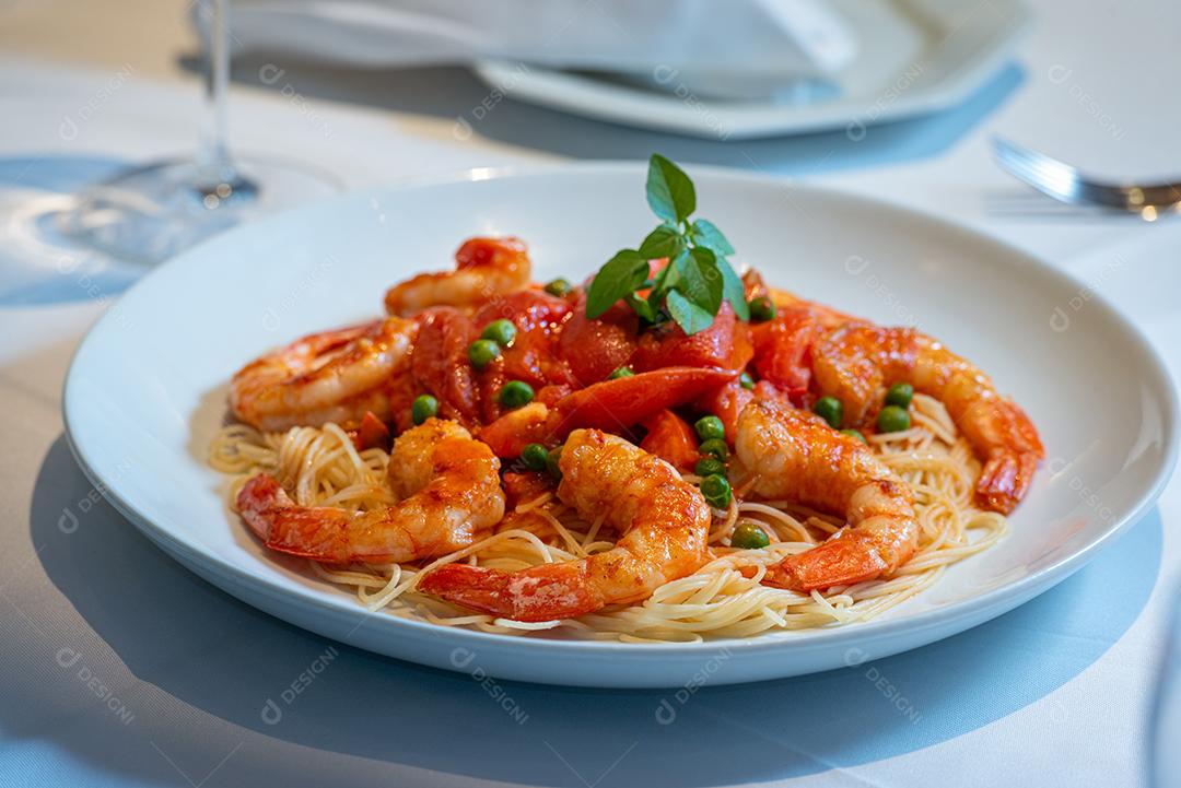 Prato de espaguete com camarão, molho de tomate e ervilhas