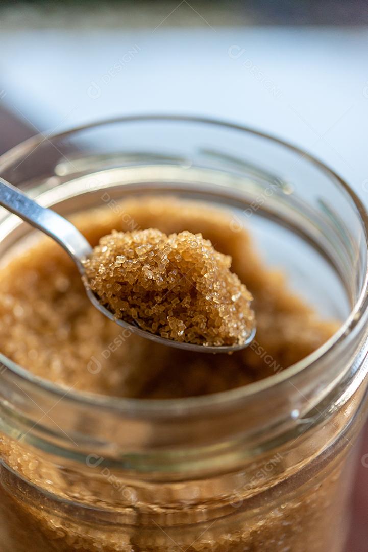 Colher de açúcar orgânico mascavo na tigela de açúcar de vidro.