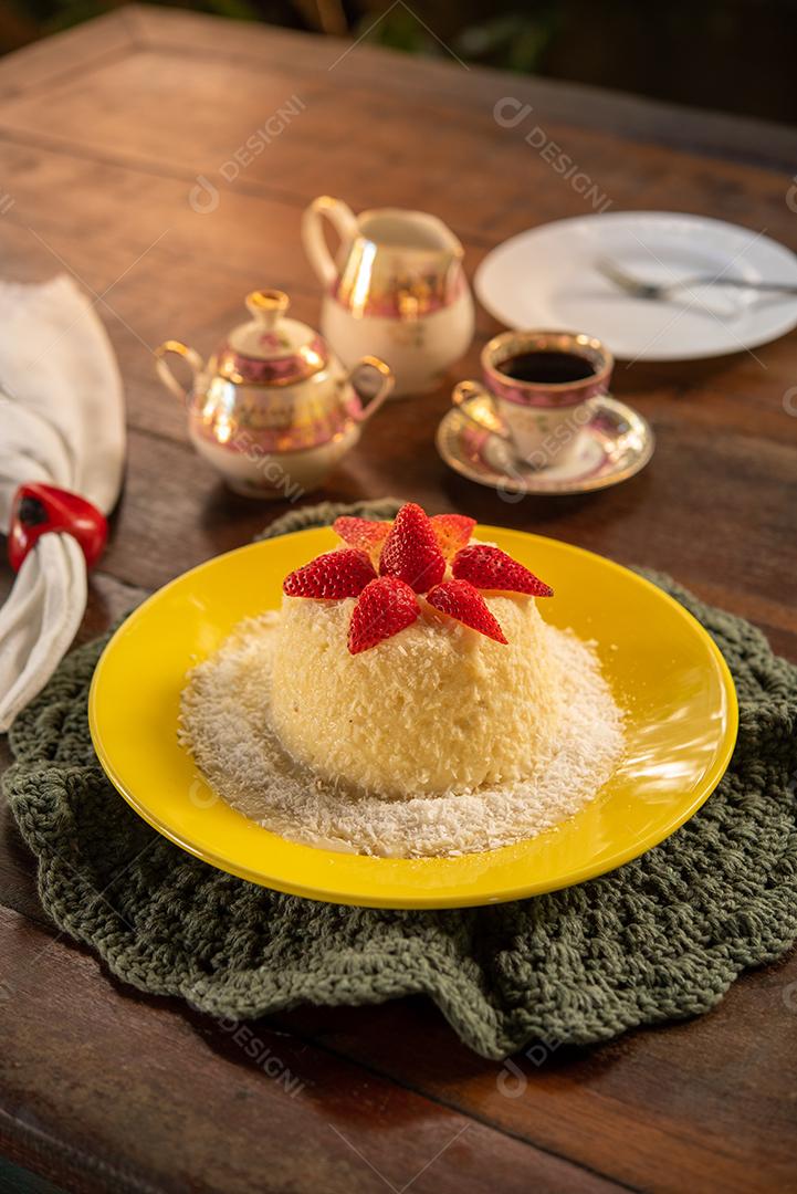 Massa de tapioca e bolo de coco, decorado com morangos, servido na mesa com café. Gastronomia, sobremesa.