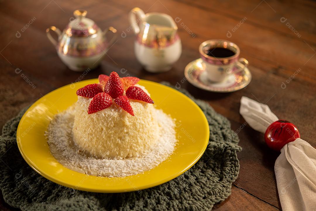Tapioca dough and coconut cake, decorated with strawberries, served on the table with coffee. Gastronomy, dessert.