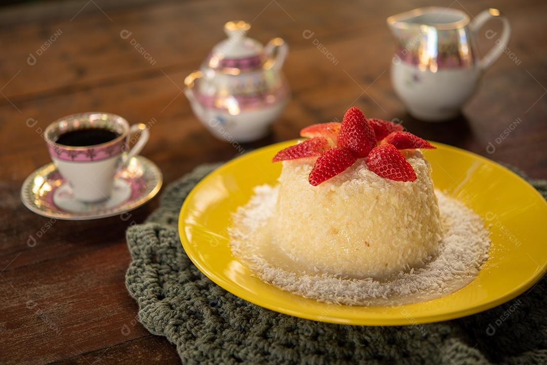 Massa de tapioca e bolo de coco, decorado com morangos, servido na mesa com café. Gastronomia, sobremesa