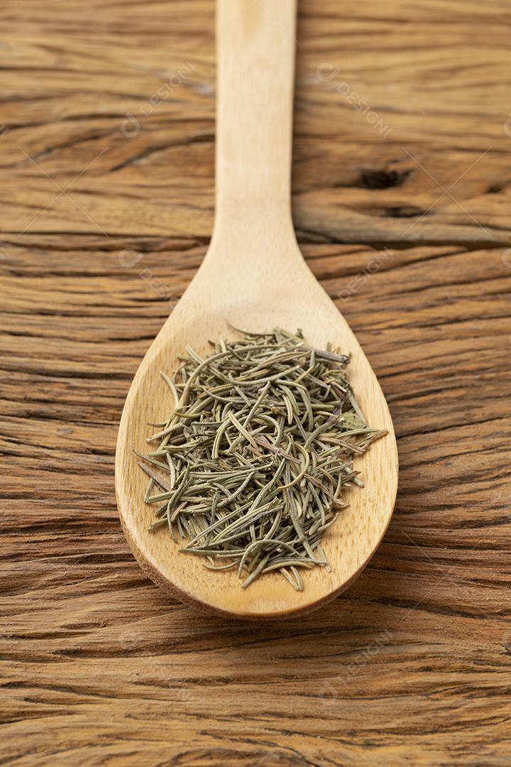 alecrim seco em uma colher de madeira. Pano de fundo alimentar