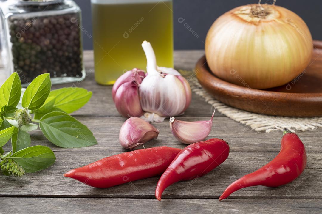 Pimentão vermelho e outros temperos sobre mesa de madeira.