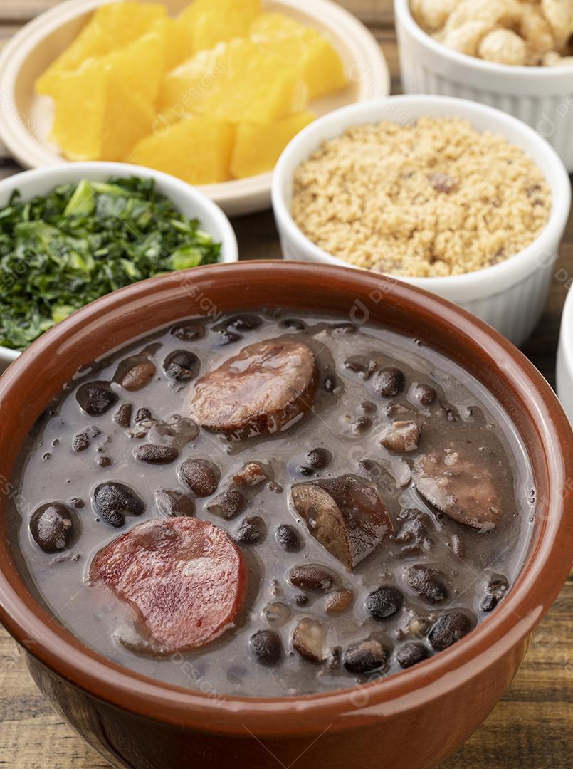 Traditional Brazilian feijoada with orange, kale and cassava flour.