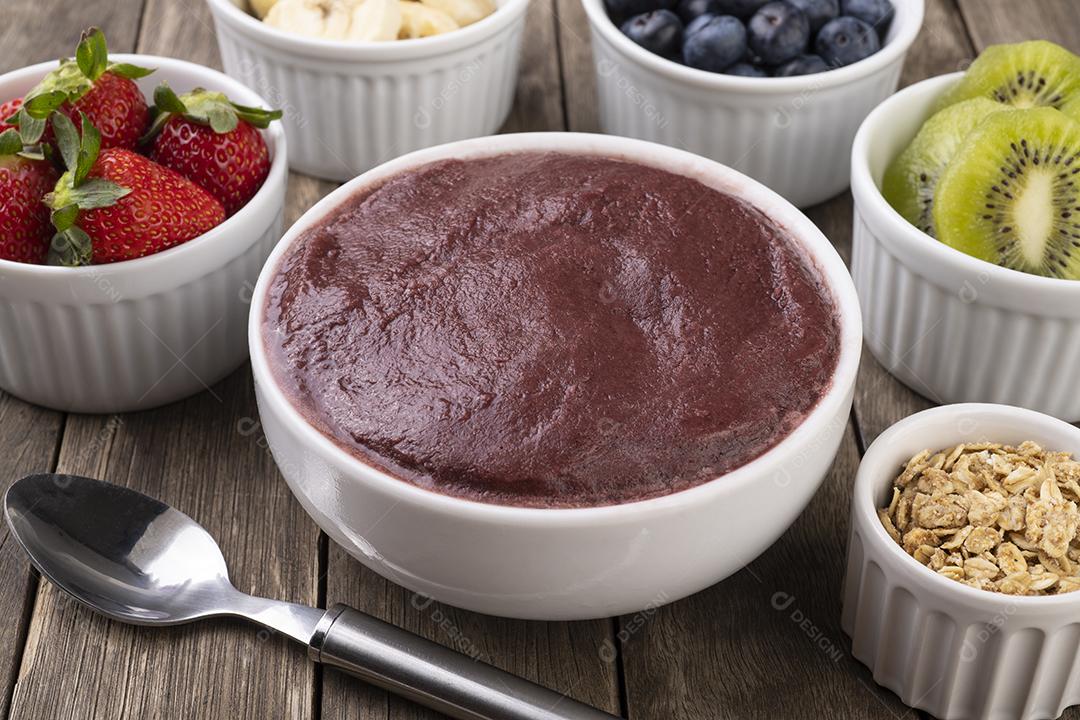 Tigela típica de açaí brasileira com frutas e muesli sobre madeira