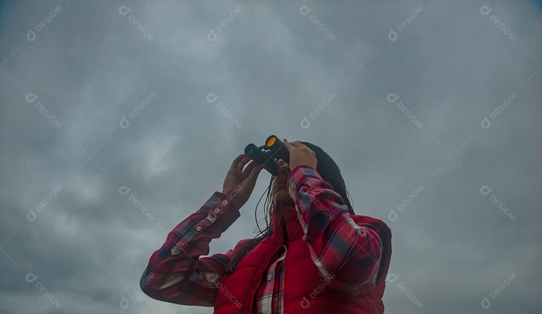 Jovem linda usando binóculos floresta