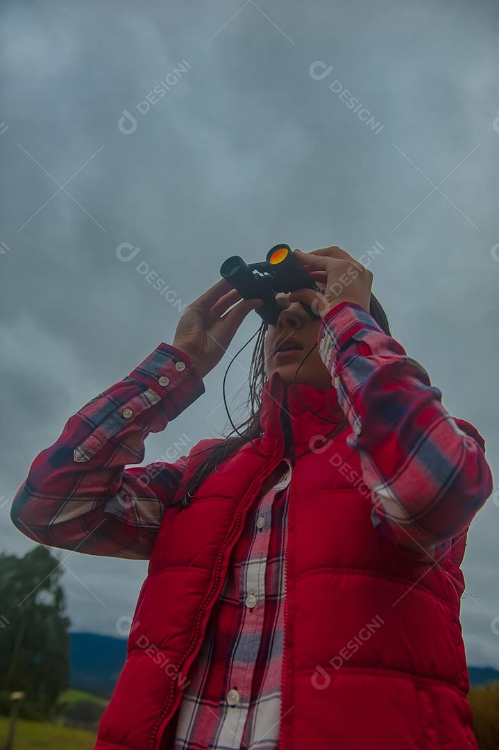 Jovem linda usando binóculos floresta