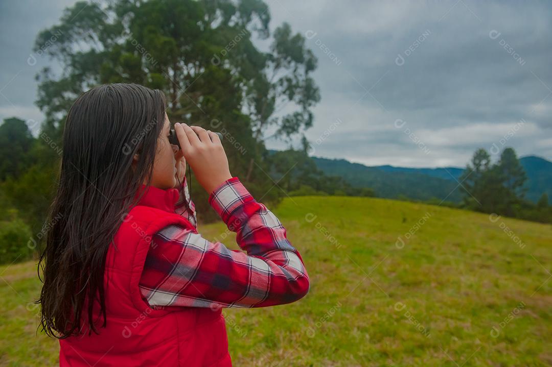 Jovem linda usando binóculos floresta