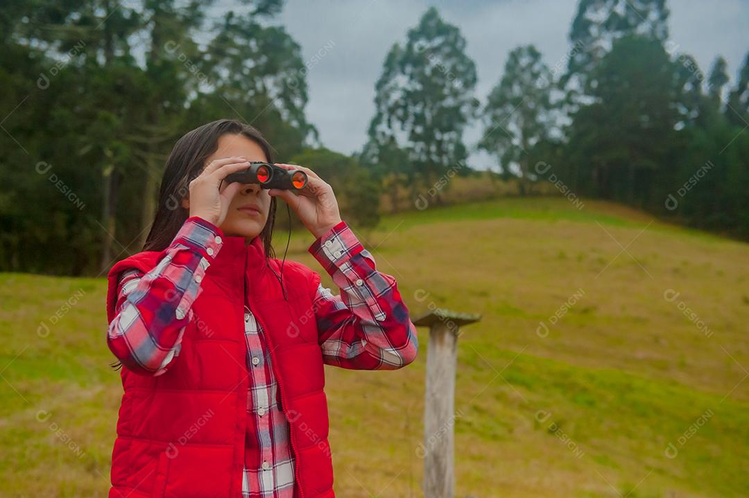 Jovem linda usando binóculos floresta