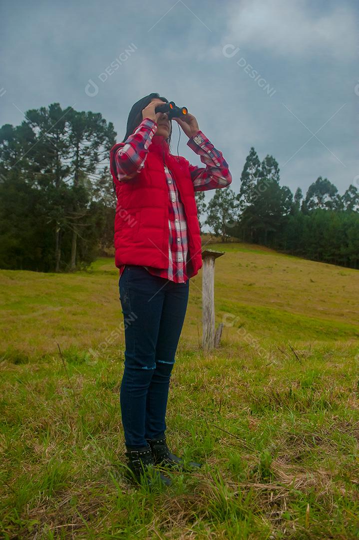 Jovem linda usando binóculos floresta