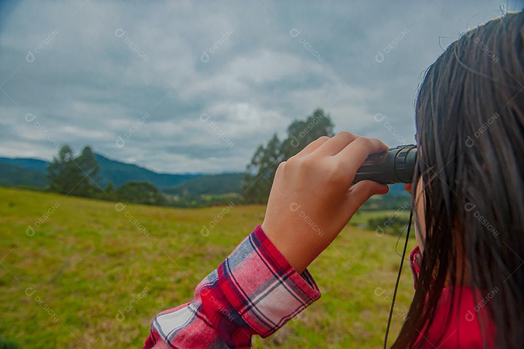 Jovem linda usando binóculos floresta