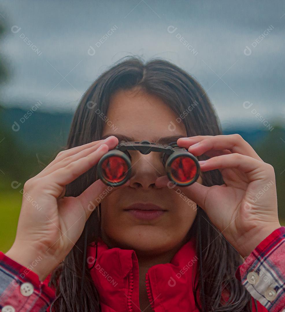 Jovem linda usando binóculos floresta