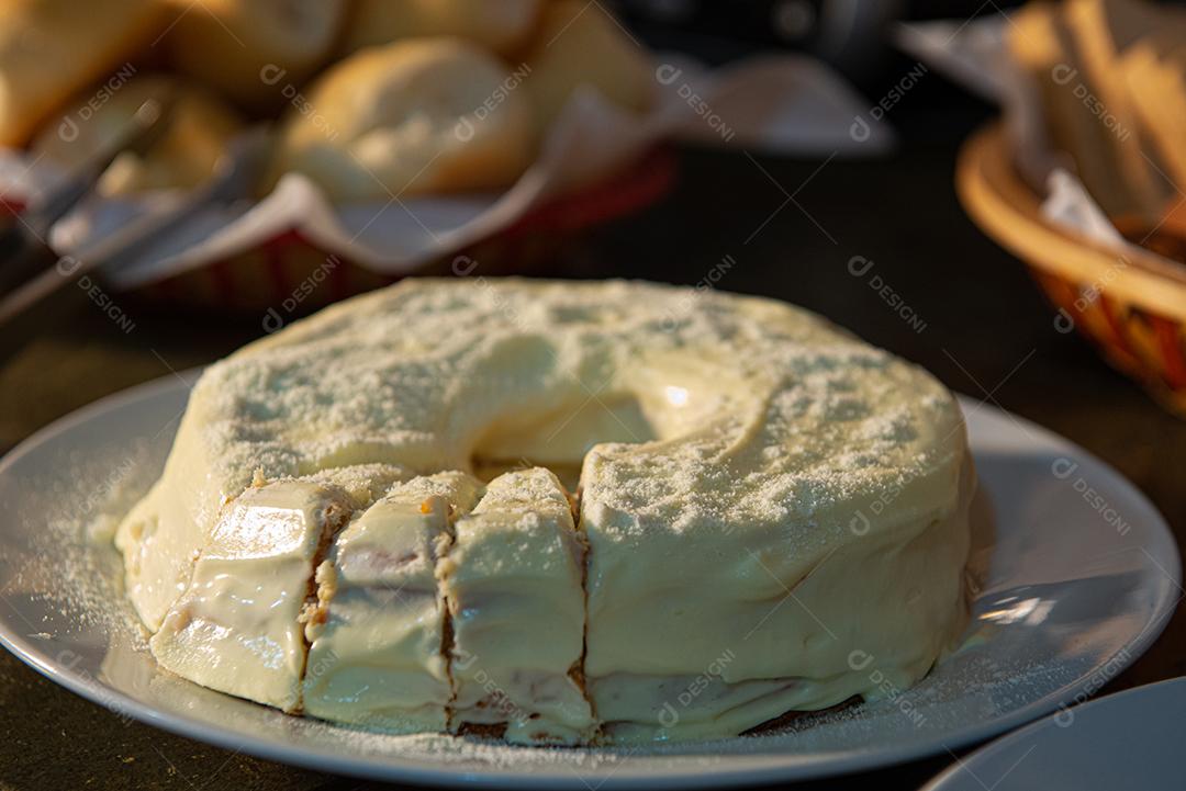 Café da manhã farto servido com bolos, tortas, geléias, bolos, queijo, presunto, café, leite.