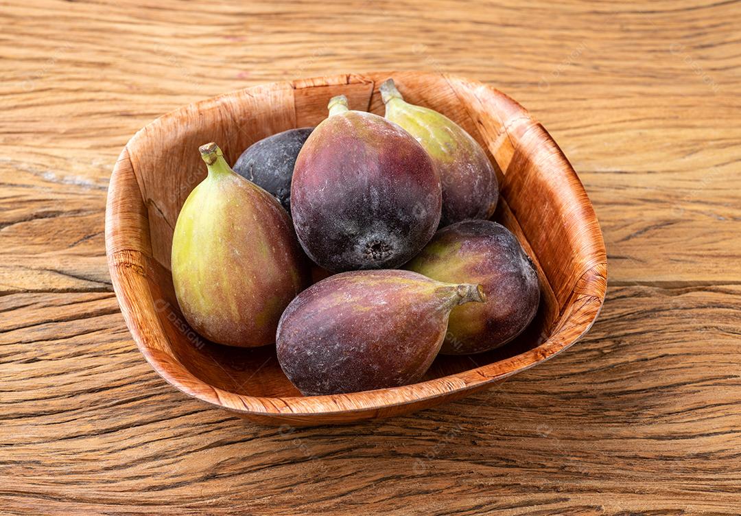 Figos em uma tigela sobre mesa de madeira