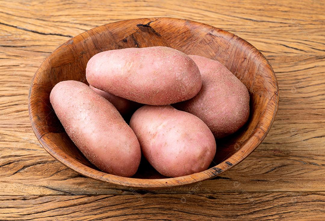 Batata vermelha em uma cesta sobre mesa de madeira.