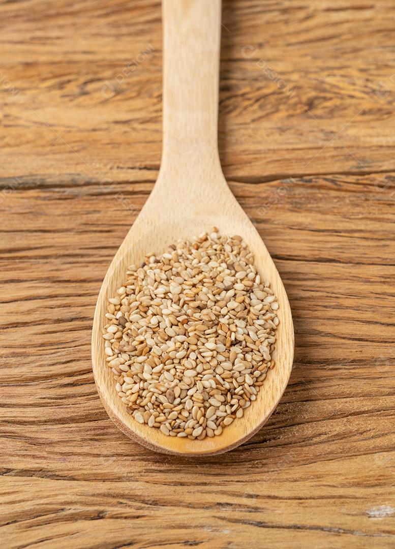 Sesame seeds in a spoon on wooden table