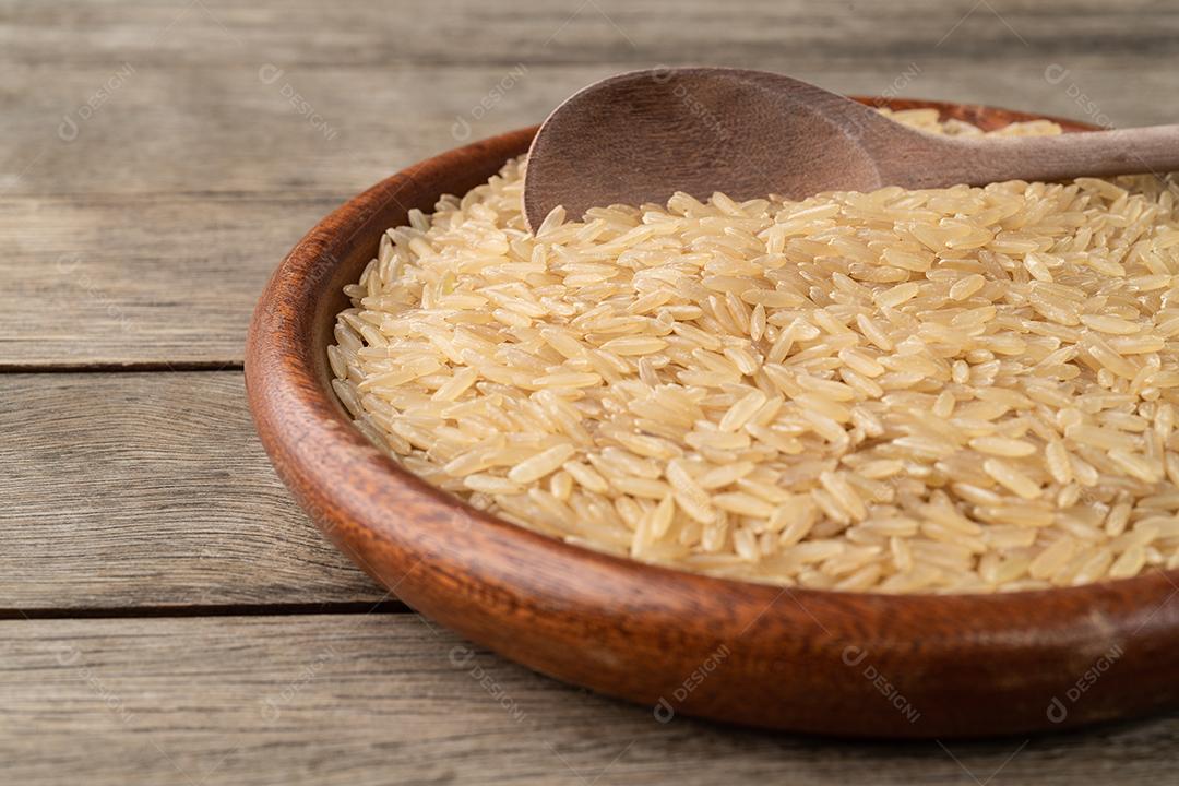 Foco estreito, arroz integral cru em um prato sobre mesa de madeira