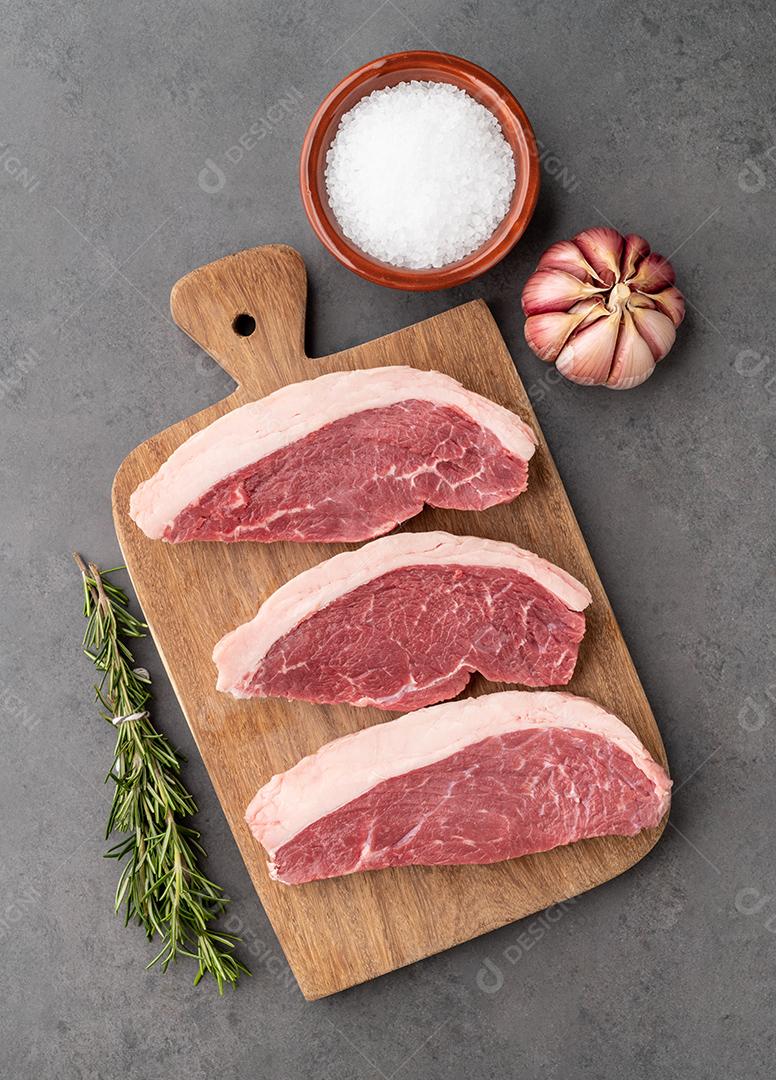 Picanha crua fatiada ou carne de alcatra sobre tábua de madeira com tempero