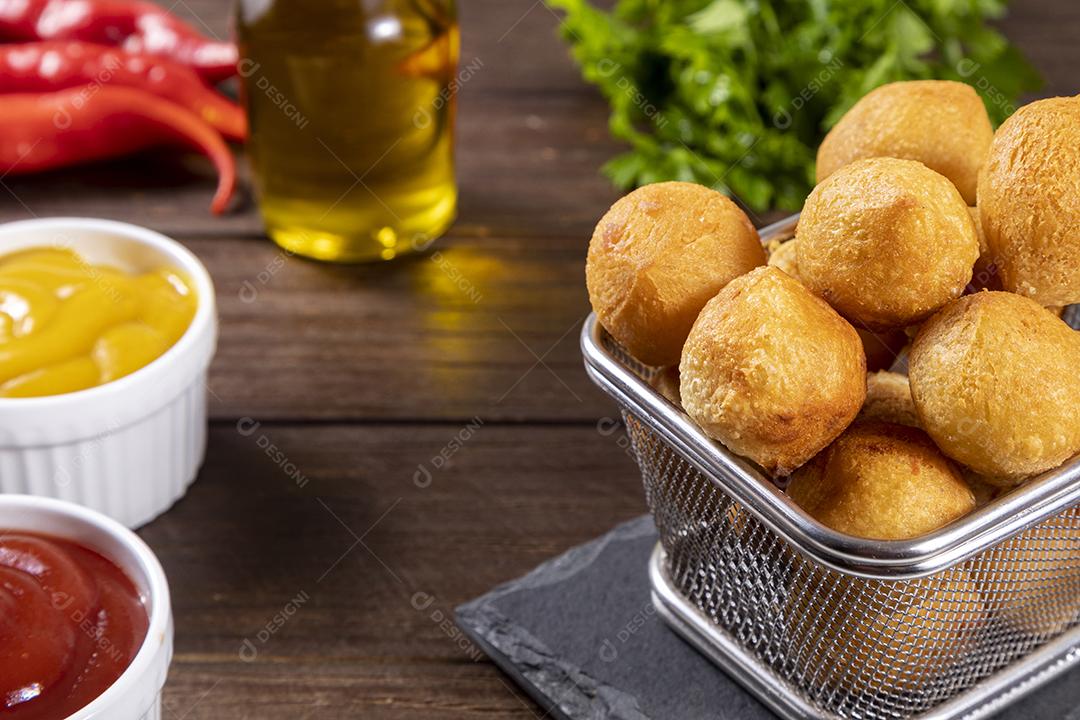 Salgado em uma saco de papel e ketchup sobre mesa madeira