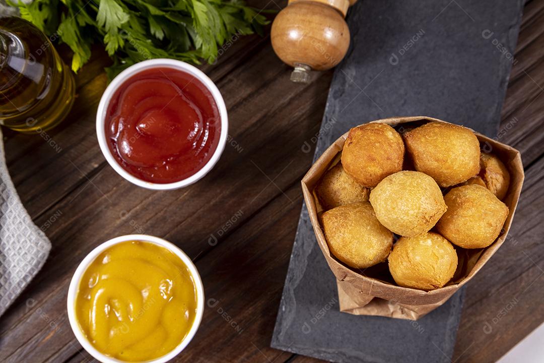 Salgado em uma saco de papel e ketchup sobre mesa madeira