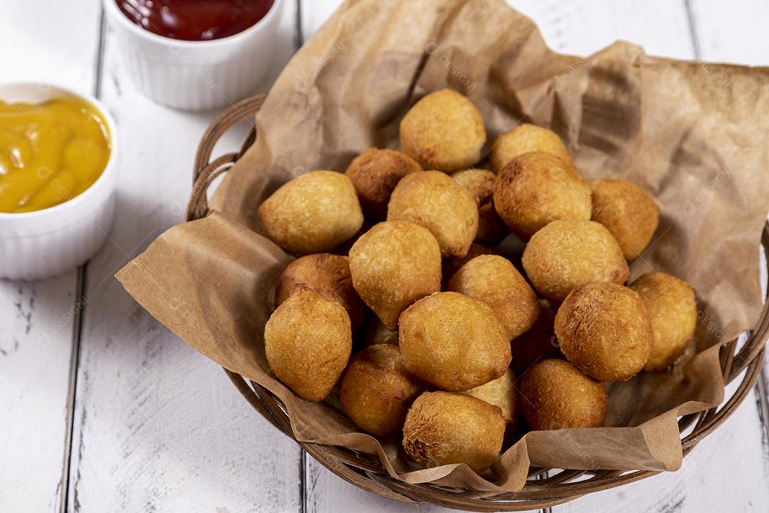 Salgados e ketchup em uma cesta com papel sobre mesa branca isolada