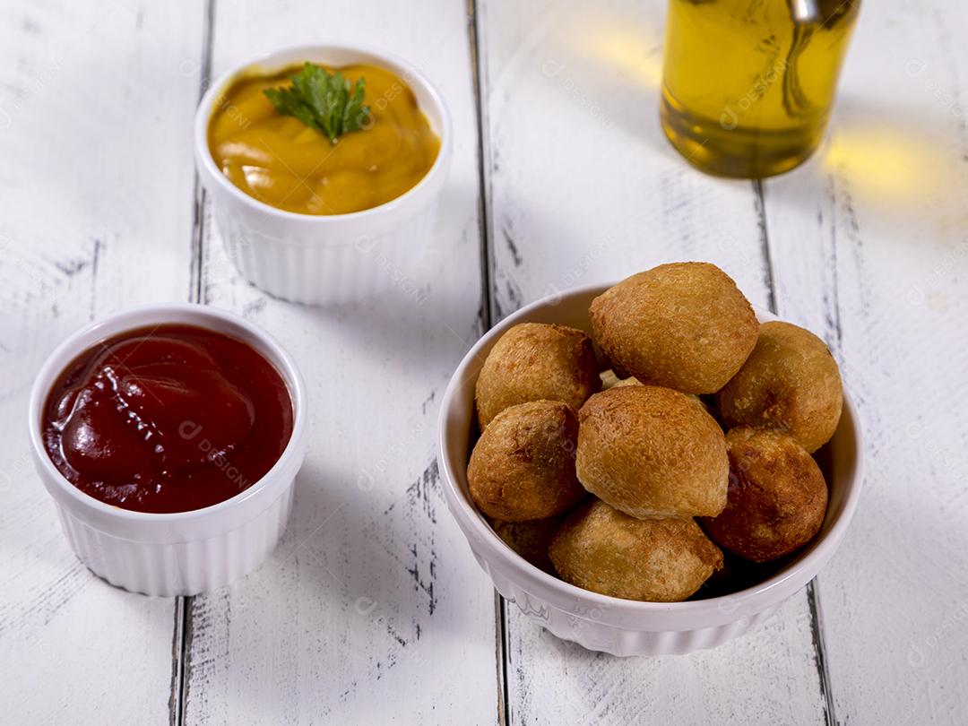 Salgados e ketchup em uma cesta com papel sobre mesa branca isolada