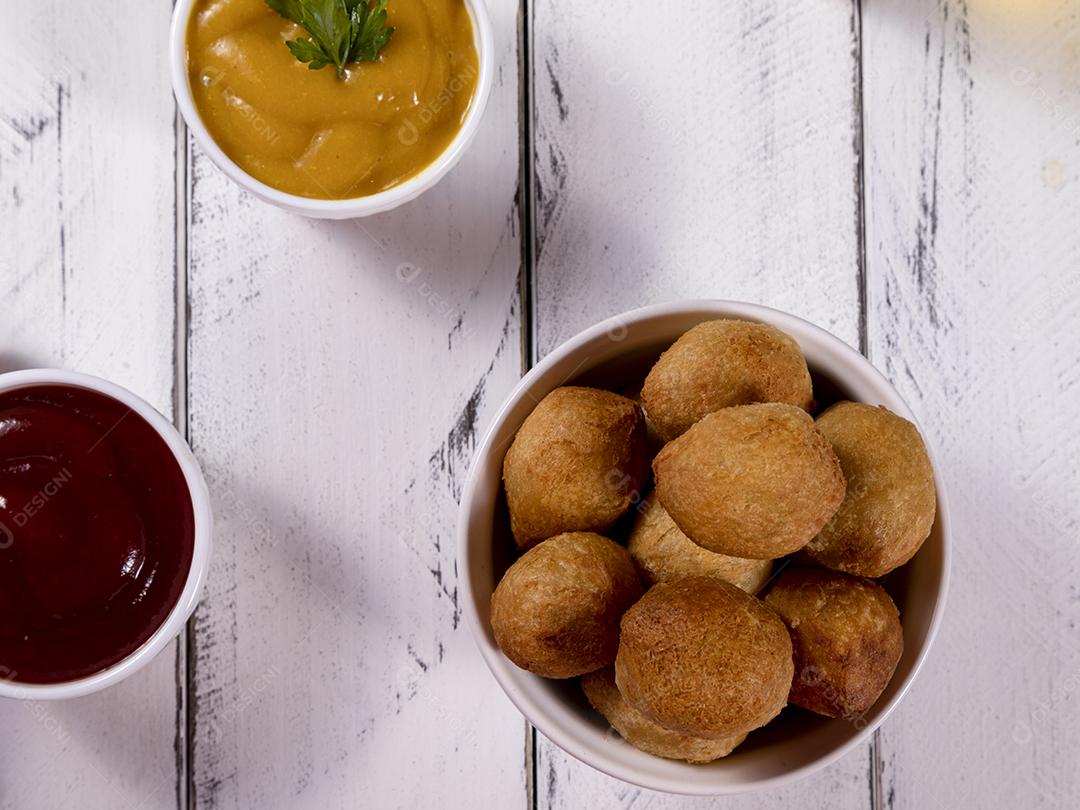 Salgados e ketchup em uma cesta com papel sobre mesa branca isolada