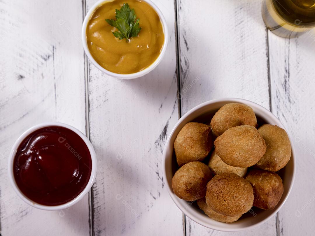 Salgados e ketchup em uma cesta com papel sobre mesa branca isolada