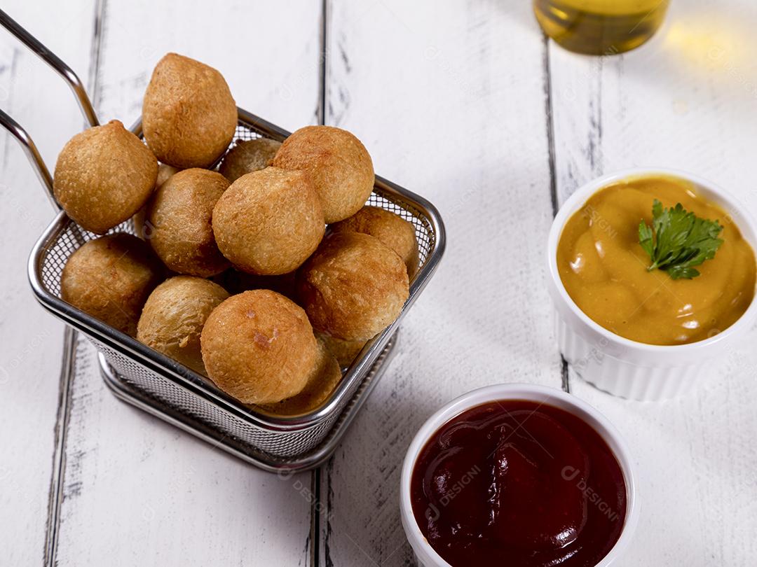 Salgados e ketchup em uma cesta com papel sobre mesa branca isolada