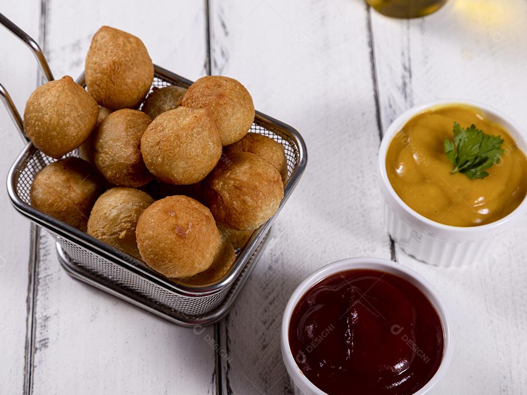 Salgados e ketchup em uma cesta com papel sobre mesa branca isolada