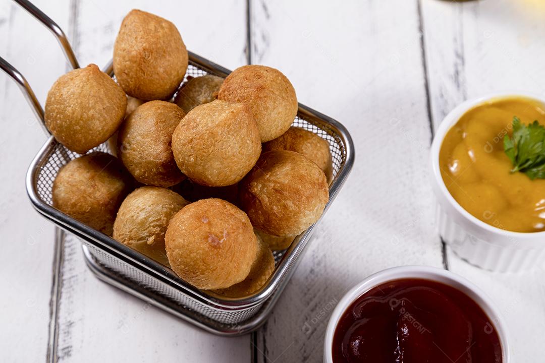 Salgados e ketchup em uma cesta com papel sobre mesa branca isolada