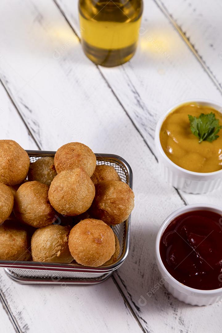 Salgados e ketchup em uma cesta com papel sobre mesa branca isolada