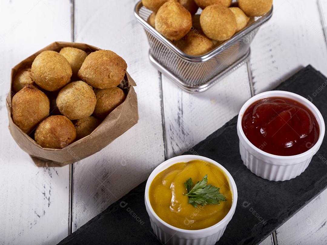 Salgados e ketchup em uma cesta com papel sobre mesa branca isolada