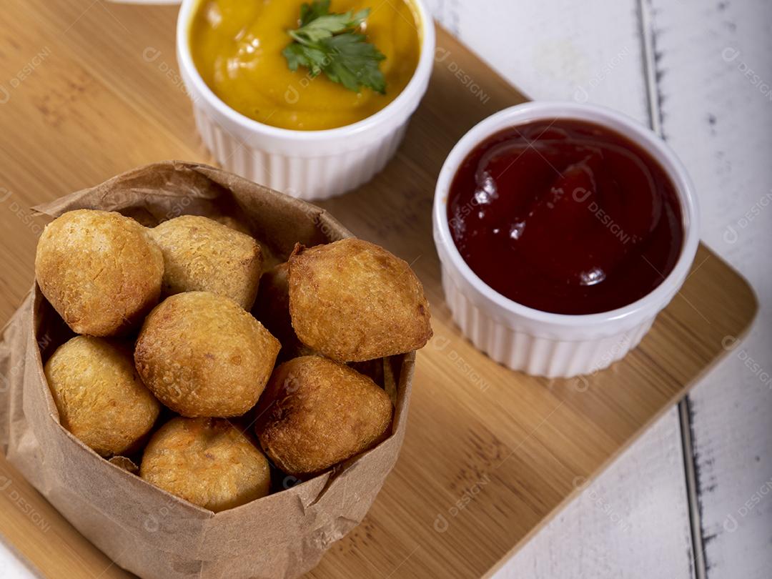 Salgados e ketchup em uma cesta com papel sobre mesa branca isolada