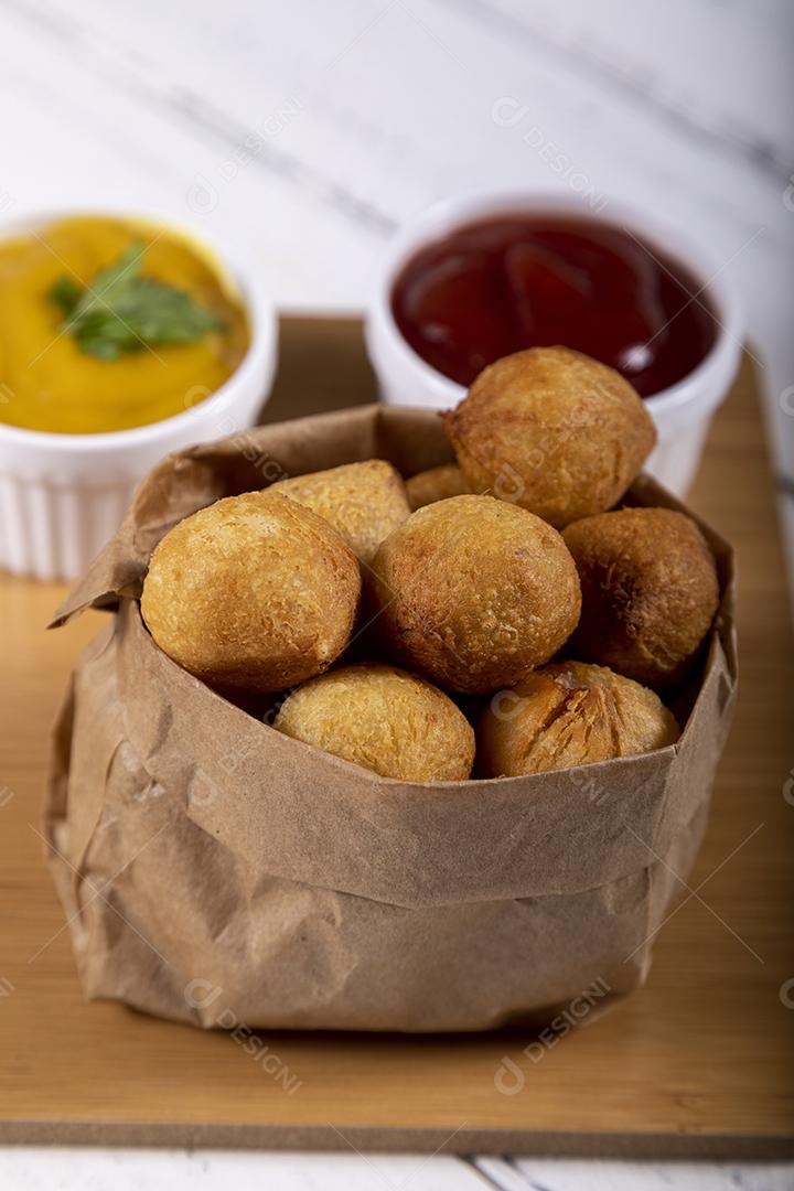 Salgados e ketchup em uma cesta com papel sobre mesa branca isolada