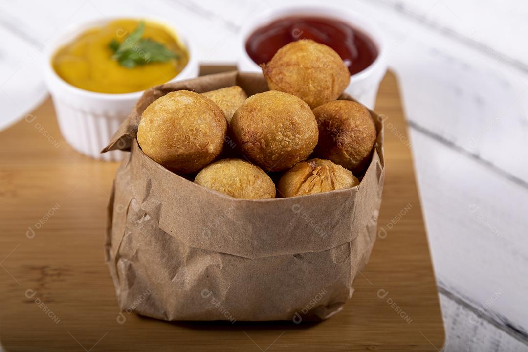 Salgados de frango fritos em saco de papel sobre fundo branco