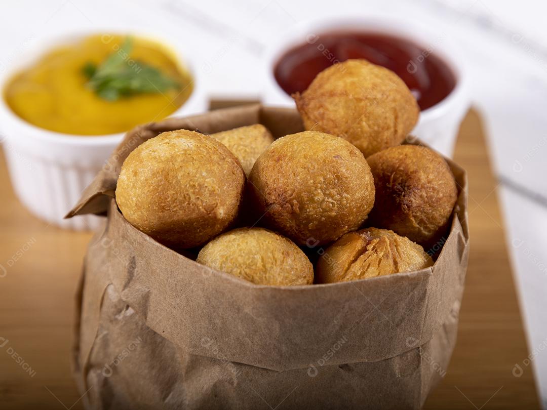 Salgados de frango fritos em saco de papel sobre fundo branco