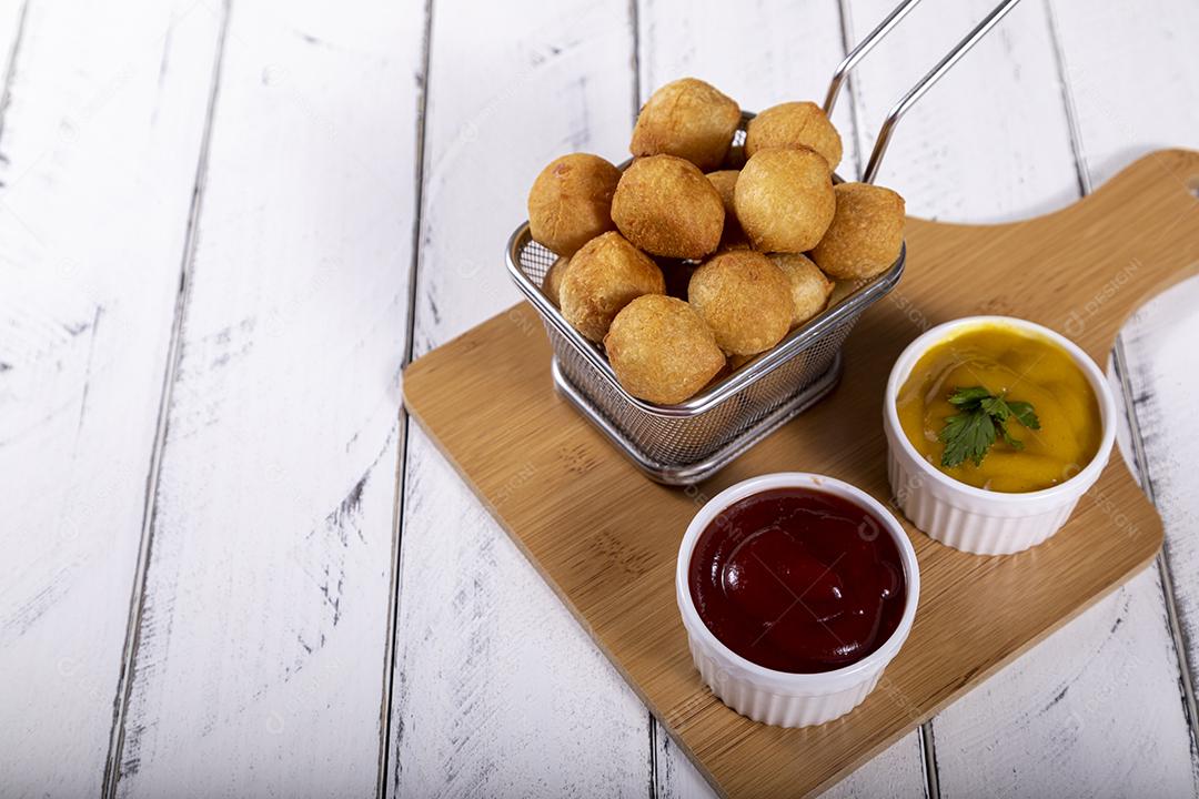 Salgados de frango fritos em tigela grade sobre fundo branco