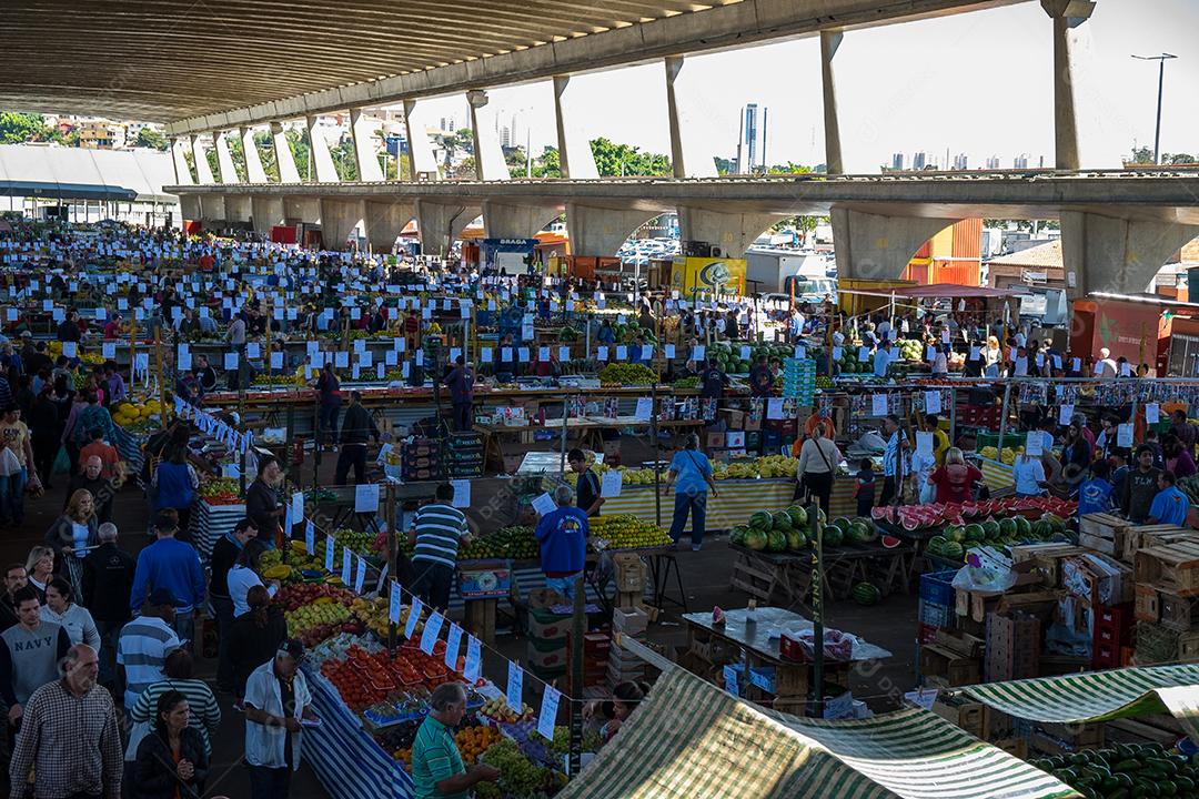 Pessoas no meio do galpão feira vendas frutas e verduras
