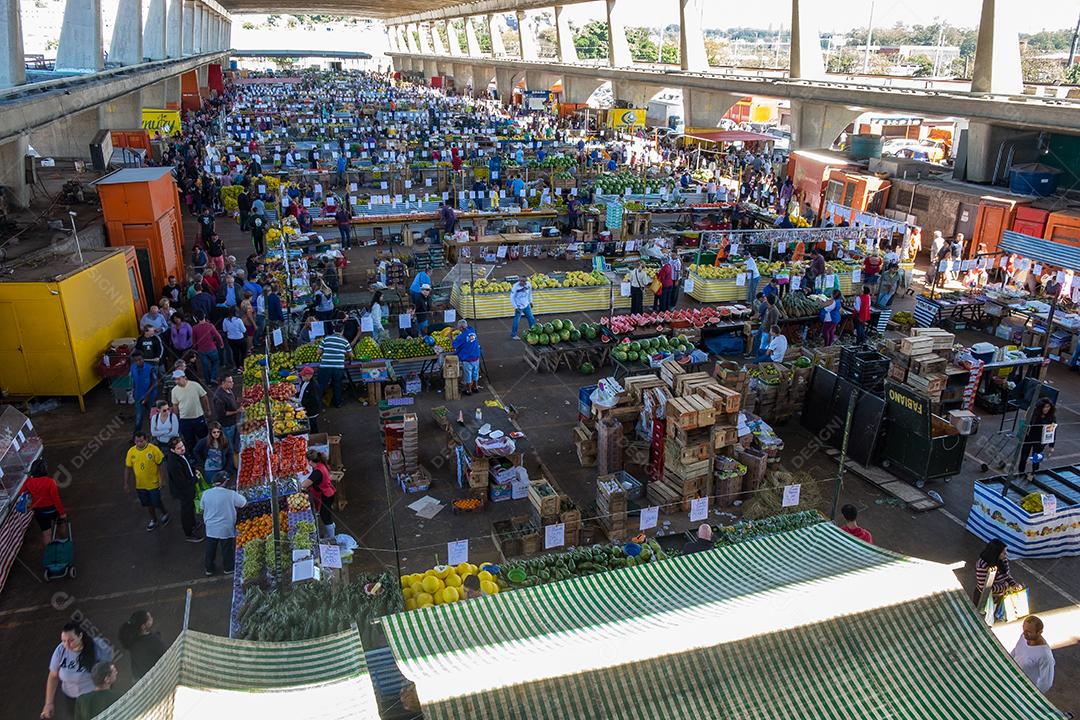 Pessoas no meio do galpão feira vendas frutas e verduras