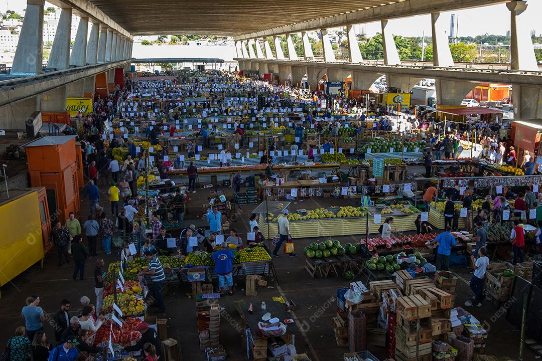 Pessoas no meio do galpão feira vendas frutas e verduras